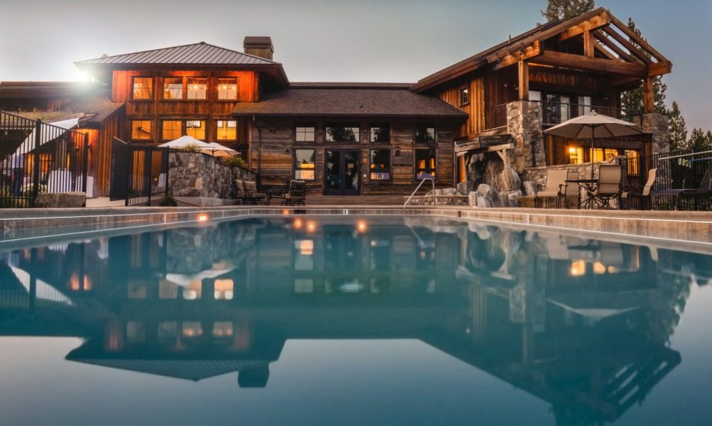 Stunning wooden villa with a large pool and cozy lights, perfect for a luxurious escape.